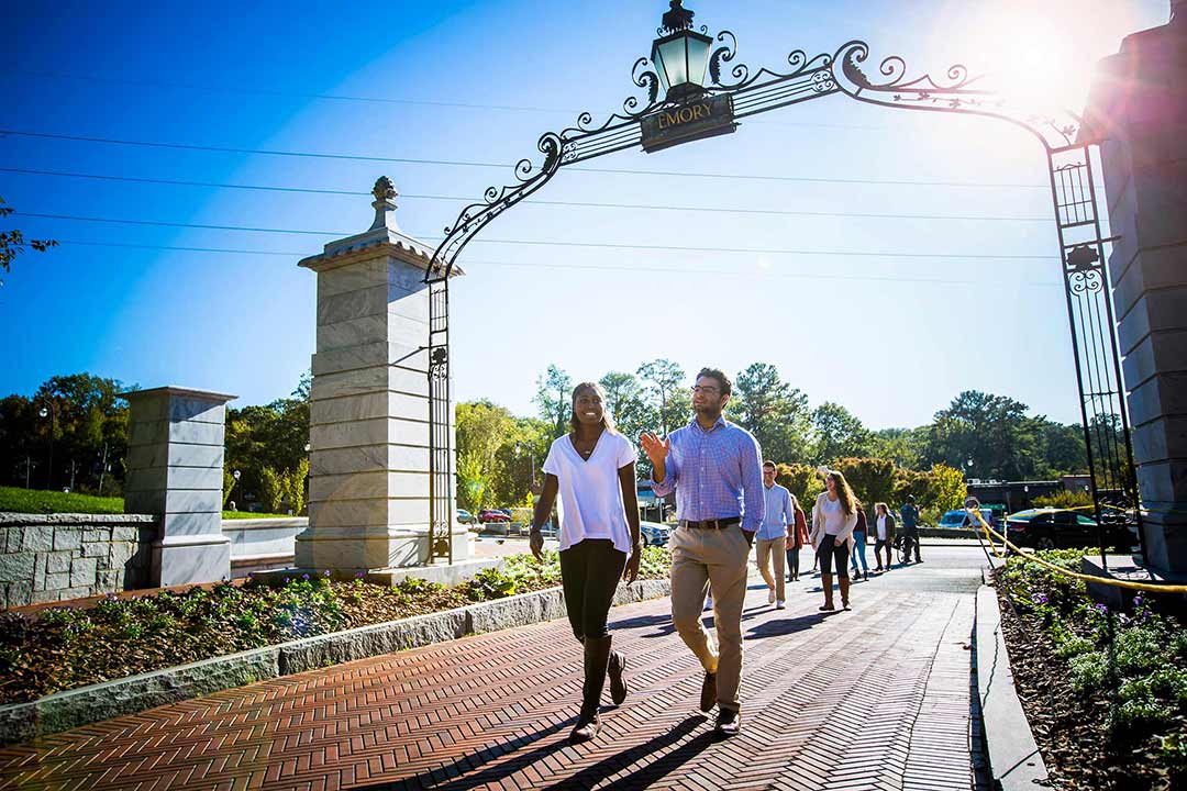 Students walk through Emory's entrance gate.